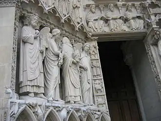 Les quatre grandes statues du piédroit de gauche du portail de la Vierge refaites au XIXe&nbsp;siècle représentent un roi non identifié et saint Denis décapité, portant sa tête et entouré de deux anges.