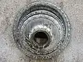 Orifice circulaire finement sculpté ; de l'eau en sort.