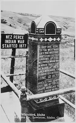 Photographie d'un monument en pierre sur lequel est inscrit : « Before you, to the westward lies the historic Whitebird battle ground of the Nez Perce indian war in whih thirty five men gave up their lives in service for their country, June 17, 1877. » et « Beneath this shaft lies one of these brave men, laid to rest where he fell. »