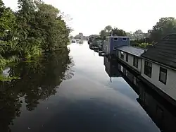 photo d'un canal bordé à gauche d'arbres et à droite de maisons