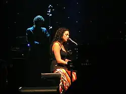 photo d'une femme en robe noire assise derrière un piano.