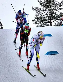 Cinq skieuses de fond, les une derrière les autres dans une descente.