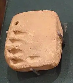 Petite tablette carrée avec des signes ronds et linéaires.