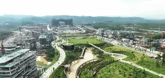 Photographie d'une ville en construction. Au premier plan, plusieurs hommes plantent et arrosent de jeunes arbres.