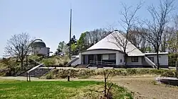 Photo couleur montrant une station d'observation astronomique avec un bâtiment (planétarium) au premier plan.