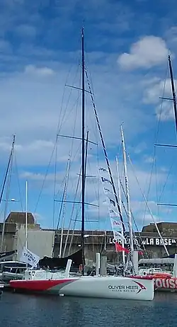 Voilier blanc et rouge vu de trois quarts avant, amarré au ponton.