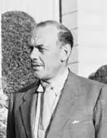 Portrait photographique en noir et blanc d'un homme en costume gris.