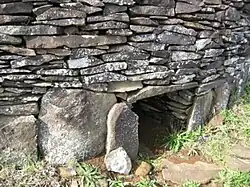 Entrée d'une hare paenga : maison familiale en pierre, en forme de bateau renversé.
