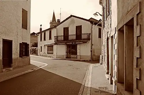 La Grande Rue avec en arrière-plan le clocher de l'église Saint-Barthélemy d'Oust.