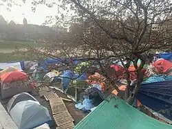 Overview of the dense encampment of colourful tents, with a line of wooden pallets in the center