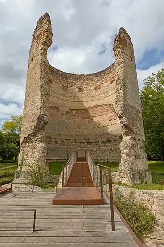 Photo représentant la tour de Vésone, une haute et large tour circulaire en briques située au milieu d'un parc arboré. Au centre, une brèche très importante court de haut en bas de l'édifice, montrant l'intérieur.