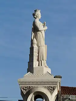 Photo de la statue en pierre calcaire claire d'une jeune femme couronnée appuyée contre une représentation du clocher de la cathédrale Saint-Front.