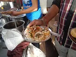 Dahi puri servis sur un stand.