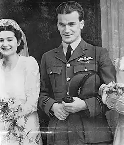 Photographie en noir et blanc d'un homme en uniforme à côté d'une femme en robe de marié.