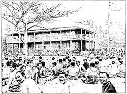 Gravure détaillée du palais royal d'Uvea en 1900. On y voit de nombreuses personnes assis tout autour.