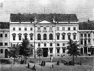 Grande maison blanche à 4 étages. Avec un fronton de style classique.