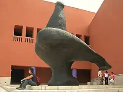 La façade rouge d'un immeuble avec une sculpture monumentale à l'avant.
