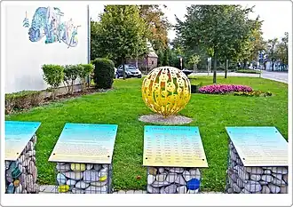 Photographie d'une boule de métal creuse fixée au sol dans un jardin public.