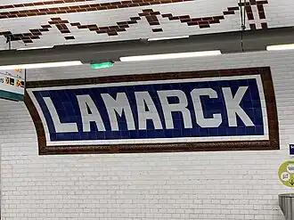 Faîence murale indiquant le nom de la station, abrégé en « Lamarck ».