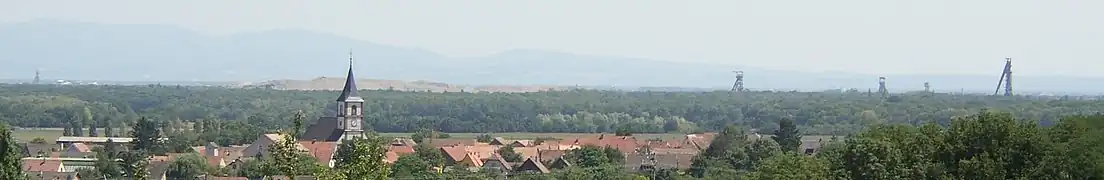 Paysage du bassin potassique vers l'an 2000, marqué par quatre chevalements, un château d'eau et un long terril et dont les parties urbanisées alternent avec la forêt du Nonnenbruch.