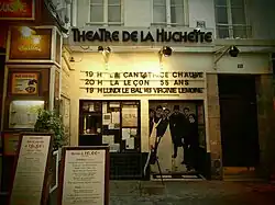 photographie en couleurs d'une devanture étroite, avec guichet, affiches et titres de spectacles