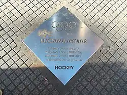 Une plaque métallique ancrée au sol sur laquelle est écrit Luciana Aymar et plusieurs lignes de palmarès.