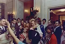 Pat Nixon tenant une enfant dans ses bras, au milieu d'autres et de visiteurs à la Maison-Blanche.