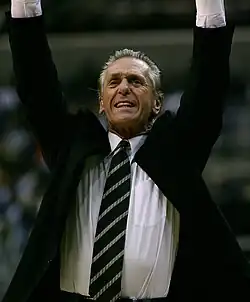 Pat Riley, en costume, les bras en l'air.