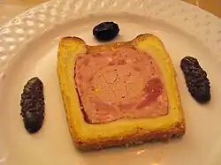 Pâté en croûte de type Richelieu, accompagné de deux moitiés de cornichon et d'une olive noire.