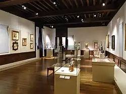 Photographie en couleurs d'une salle avec des tableaux.