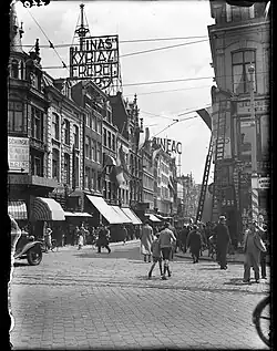 Entrée de la rue en 1934. On aperçoit l'enseigne du Cinéac et une publicité pour les cigarettes Kyriazi Freres&nbsp;(en). Photo de Paul Guermonprez.
