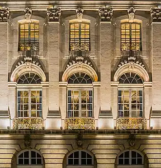 Effets de lumières sur un mur ouvragé percé d'ouvertures vers des pièces éclairées.