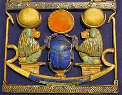 Le pectoral appartient à un grand collier. Dans le cadre, on observe une barque d'or incrustée de cornaline, de lapis et de feldspath, qui possède 2 pavillons en or sur lesquels sont assis 2 singes hamadryas (dieu Thot) se faisant face. Leurs têtes sont surmontées d'un croissant lunaire en argent soutenant l'image de la lune en or. Au centre, un scarabée en or et lapis-lazuli pousse devant lui la boule rouge du soleil faite de cornaline cerclée d'or.