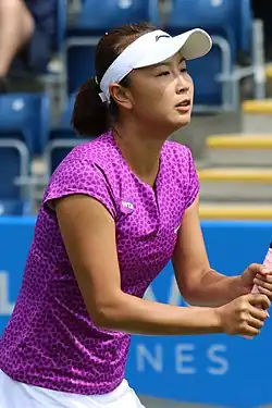 Une joueuse de tennis avec un haut rose violet et une visière blanche
