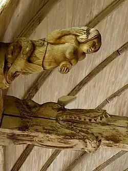 Deux sculptures bois. Sirène tenant un peigne d'une main et un miroir de l'autre. Juste à côté, tête de monstre avalant une poutre.