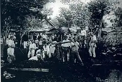 Photo noir et blanc d'un grand groupe de personnes portant des pelles et des seaux de terre.