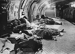 Des personnes allongées sous des couvertures sur un quai de métro.