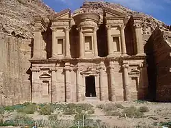 Monument sculpté dans la roche. Une personne se trouve sur le seuil.