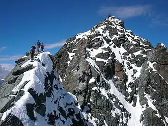 Alpinistes au sommet du Kleinglockner avec le Großglockner en arrière-plan.