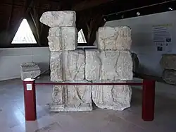 Photographie en couleurs d'un assemblage de blocs sculptés représentant un personnage.