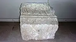 Photographie en couleurs d'un bloc de pierre gravé de décors géométriques et floraux.