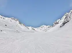 Photographie de la piste de ski Bouchet à Orelle avec des piquets rouges et des montagnettes en neige.
