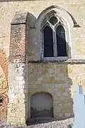Contrefort, fenêtre gothique et porte basse murée.