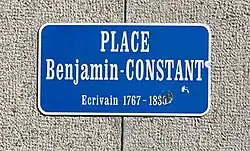 Plaque bleue portant le texte « Place Benjamin-CONSTANT / Ecrivain 1767-1830 ».
