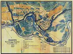 Plan d'une ville. La rivière forme un méandre, avec sur la partie haute de l'image une ville alignée sur une avenue rectiligne. Dans un méandre au centre-droit se trouve une autre partie de la ville avec des rues plus organiques.