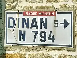 Plaque Michelin scellée dans le mur d’une maison.