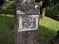 Plaque fixée sur une ancienne croix de pierre (XVIIe&nbsp;siècle) dans l'ancien cimetière.