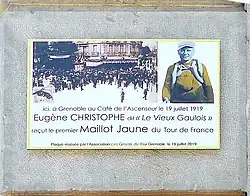 Plaque colorée portant des inscriptions, collée sur un mur en pierre.