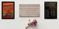 Photographie de trois plaques commémoratives posées les unes à côtés des autres. Sur la première est reproduite l'Affiche rouge. Sur la seconde, on peut lire « Aux héros du groupe Manouchian. Arméniens, Juifs, Français, Etrangers, Patriotes, Résistants. Ils sont morts pour la France et la Liberté. Passant, souviens toi ». Sur la troisième, on peut lire un extrait du poème d'Aragon et le nom des 23 résistants exécutés.