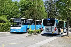 Photographie en couleurs d’un autocar du réseau de Rumilly et d’un autobus du réseau d’Annecy, les deux dans des sens opposés.
